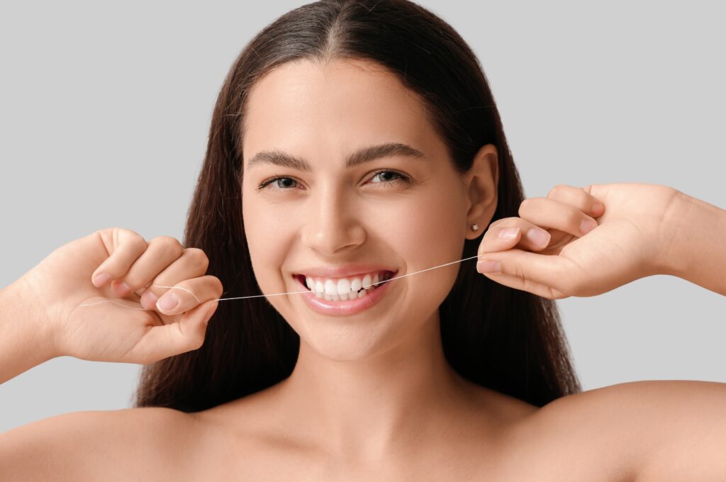 Person flossing teeth with dental floss